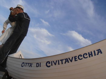Low angle view of man holding camera against sky