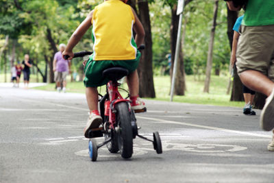 Rear view low section of boy riding bicycle on road