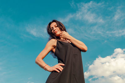 Low angle view of woman standing against blue sky