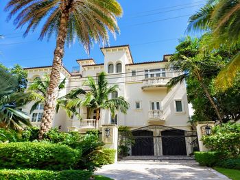 Palm trees by residential building against sky