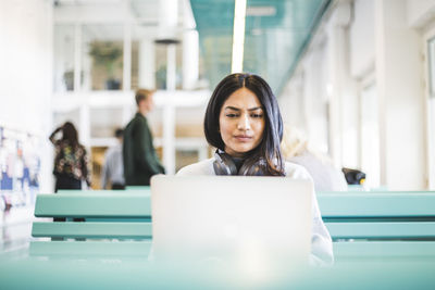 Young female student using laptop at cafeteria in university