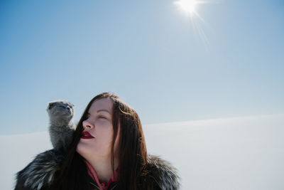 Woman with cat against blue sky during sunny day