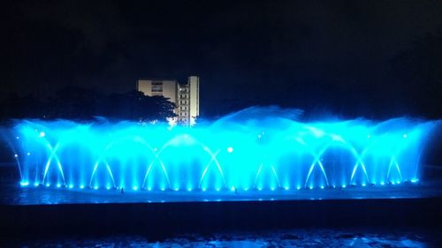 Illuminated fountain against blue sky at night