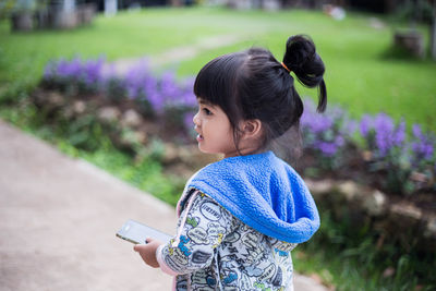 Girl looking away holding smart phone at park