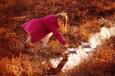 Girl in the spring on the creek launches paper boats