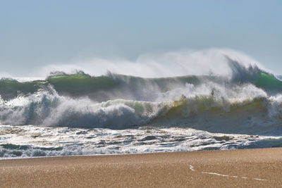 Waves rushing on shore against sky