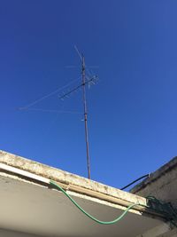 Low angle view of telephone pole against clear blue sky