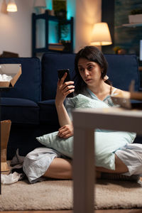 Young woman sitting on sofa at home