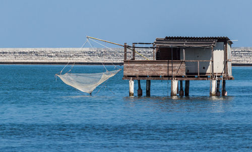 View of building on sea with fishing net