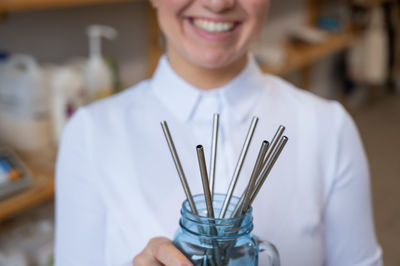 Midsection of waitress holding drinking straw