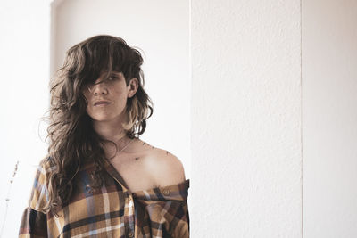 Natural girl with wild hair and freckles looks into camera in window