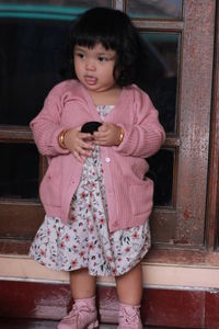 Full length of cute girl holding pink while standing outdoors