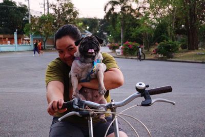 Portrait of woman with dog riding bicycle on road