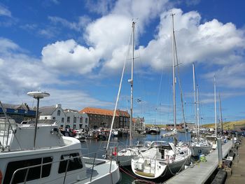 Sailboats moored at harbor against sky