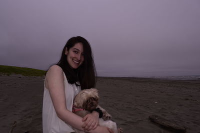 Portrait of woman with dog on beach