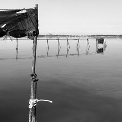 Wooden post in lake against sky