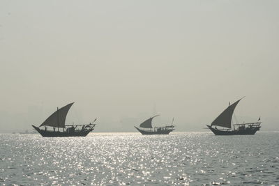 Sailboats in sea against clear sky