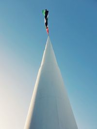 Low angle view of cross against building against clear blue sky