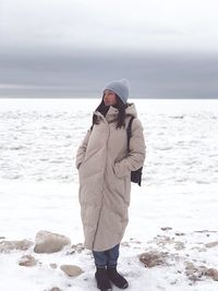 Woman standing in warm clothing on snow covered field