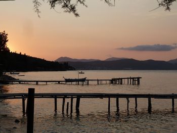 Pier on lake against sky during sunset