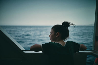 Rear view of man looking at sea against clear sky