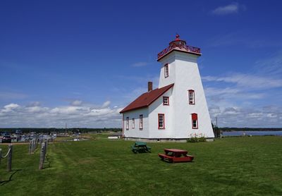 Lighthouse on field against sky