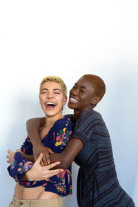 Portrait of cheerful lesbian couple embracing against white background