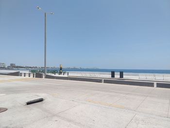 Street by sea against clear sky