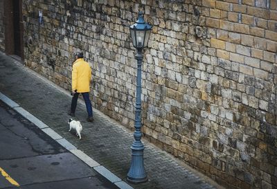 Rear view of man standing against brick wall