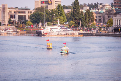 Boat sailing in sea against buildings in city