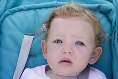 Close-up portrait of cute baby girl with blue eyes in stroller
