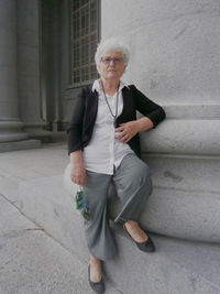 A seventy year old caucasian woman posing near a column