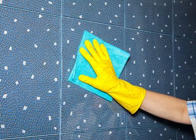 Person wiping tile wall at home