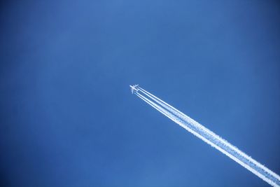 Low angle view of airplane flying in mid-air against blue sky