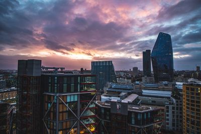 Modern buildings in city against sky at sunset