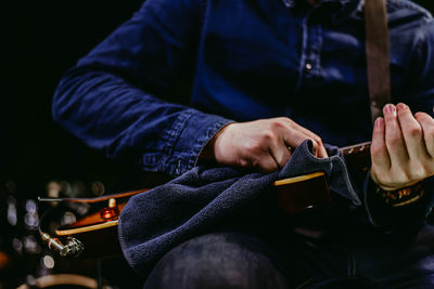 Midsection of man cleaning guitar