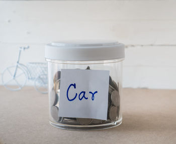 Close-up of glass of jar on table against wall