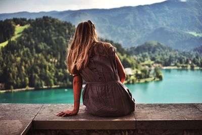 Rear view of woman looking at lake against mountain