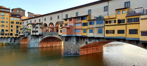 Arch bridge over river against buildings in city