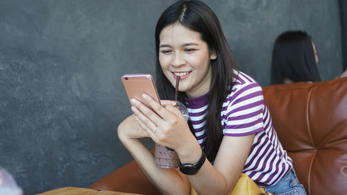 Young woman using mobile phone while sitting in mirror