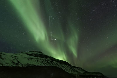 Low angle view of mountain against aurora borealis at night