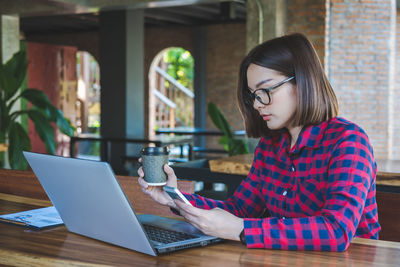 Woman looking away while sitting on table