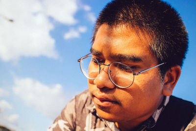 Close-up portrait of man with eyeglasses against sky