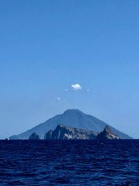Scenic view of sea and mountains against blue sky