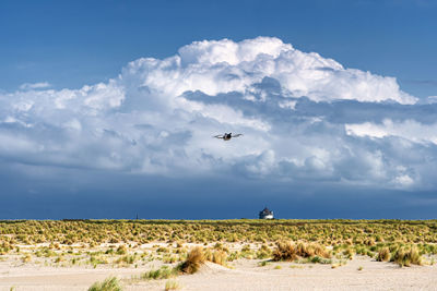 A tiny drone hovering above the kijkduin beach of the hague with a large thunderstorm