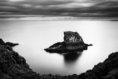 Rock on sea shore against sky