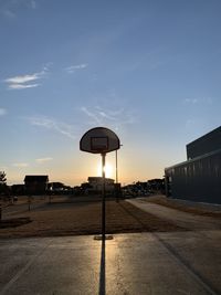 Road by building against sky during sunset