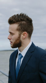 Close-up of man in suit against sea