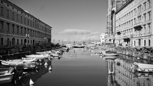 Boats moored in canal amidst buildings in city