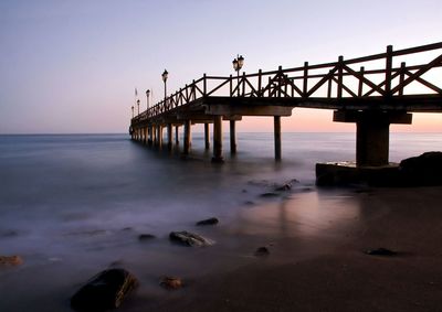 Pier over sea against sky during sunset